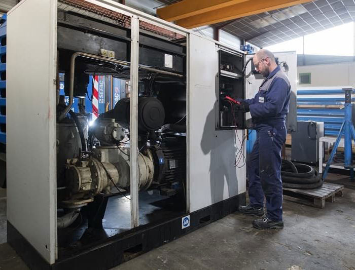 technicien en train d'effectuer une opération de maintenance sur un compresseur d'air 